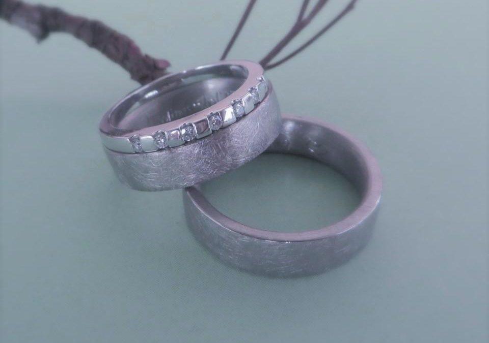 Zylindrische Trauringe aus eismattem Weißgold mit ansteckbarem Verlobungsring.