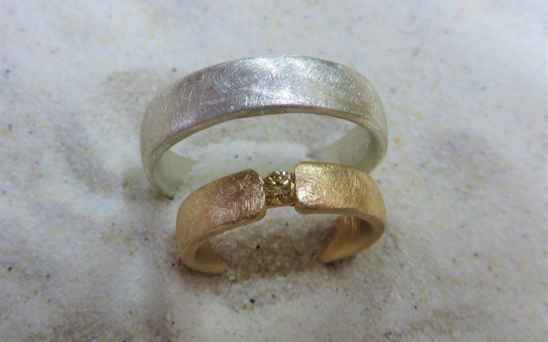 Schlichte zweifarbige Trauringe in Silber und Roségold in eismatt mit gelbem Brillanten.
