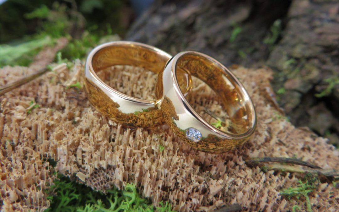 Schlichte glänzende Trauringe in Roségold mit weißem Brillant.