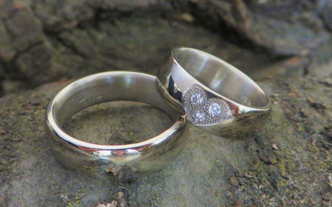 Polierte Trauringe in Weißgold mit Herz das mit Brillanten ausgefasst ist.