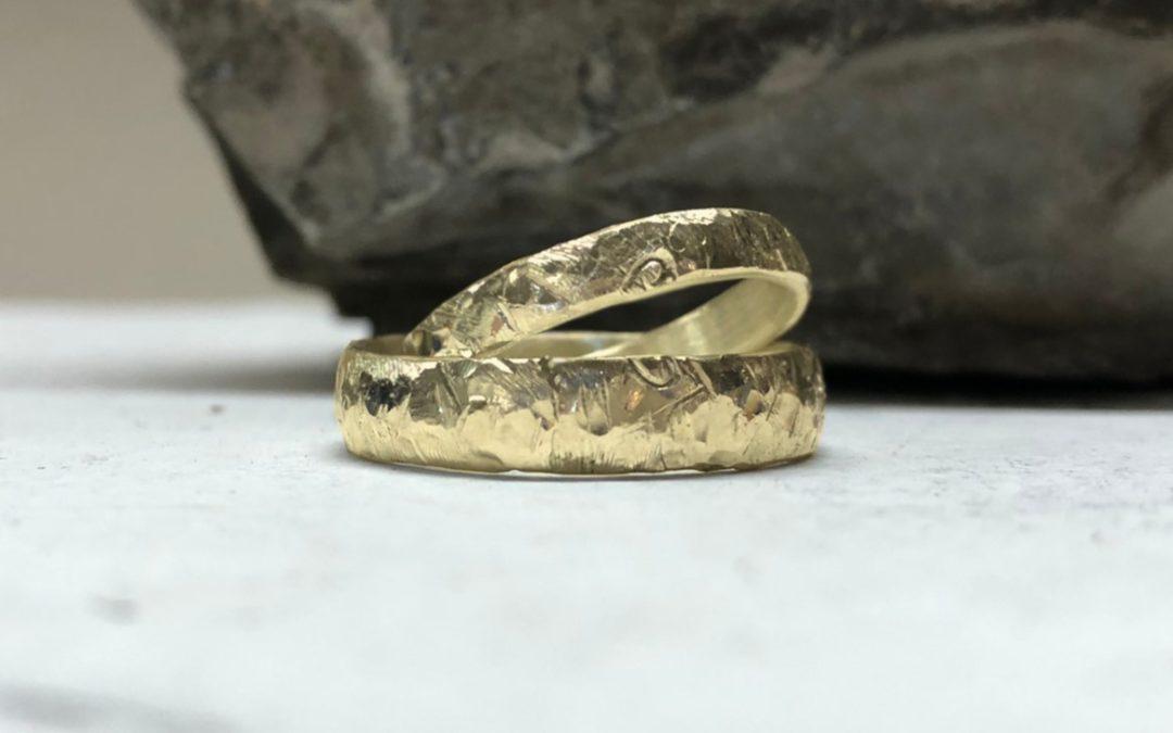 Eheringe mit Herzen auf beiden Ringen mit Herzschlagmuster und Bergweltmuster in Gold