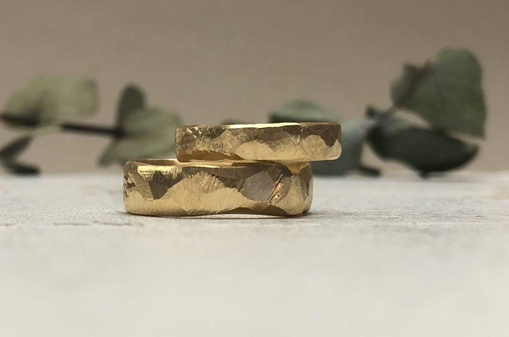 Facettierte breite Hammerschlagringe in Gold geschmiedet mit Felsenmuster.