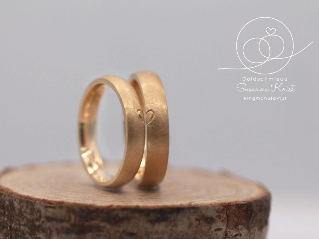 Herzchenringe aus Gold, auf jedem Ring ist eine Herzhälfte.