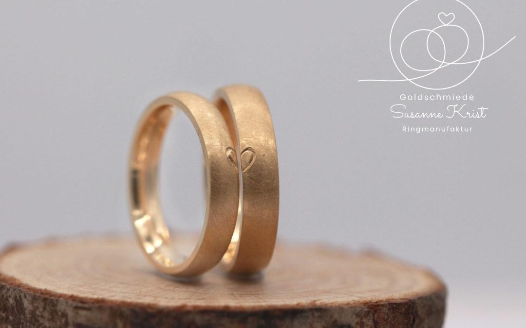 Herzchenringe aus Gold, auf jedem Ring ist eine Herzhälfte.
