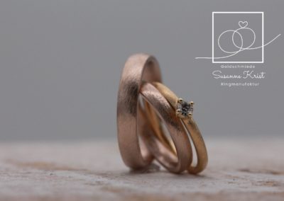 Haselnussgold Trauringe mit Dünemuster, dazu ein Goldverlobungsring.