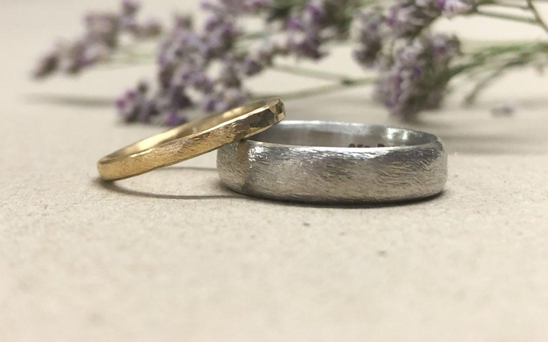 Schmaler dünner Frauenring in Gold und breiter weisser Männerring mit Struktur Düne