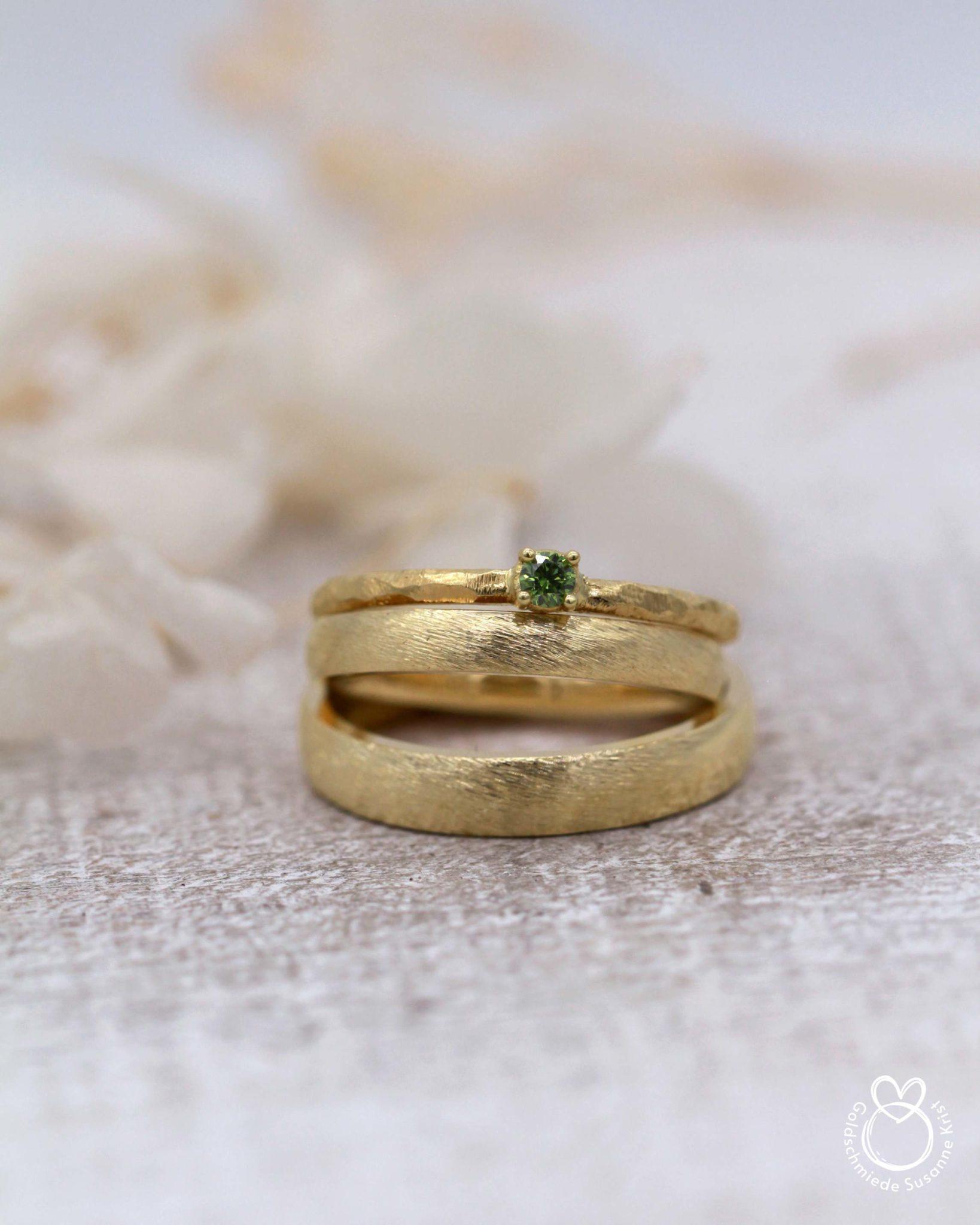 Verlobungsring mit grünem Stein Olivi und Trauringe mit Dünemuster in Gold Verlobungsring mit grünem Stein Olivi und Trauringe mit Dünemuster in Gold